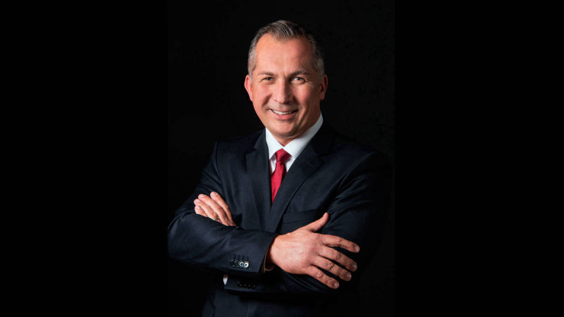 Businessportrait eines Mannes mit roter Krawatte vor schwarzem Hintergrund
